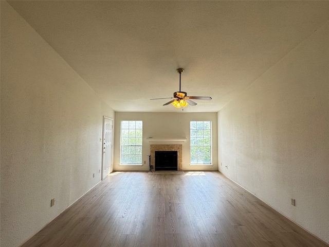 7400 Bellerive Dr Unit 1004, Houston, TX 77036 - unfurnished living room with wood finished floors, ceiling fan, a textured wall, and a fireplace with flush hearth