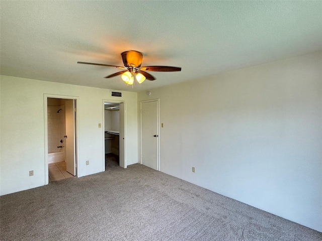 7400 Bellerive Dr Unit 1004, Houston, TX 77036 - unfurnished bedroom with carpet floors, connected bathroom, a spacious closet, a ceiling fan, and a textured ceiling
