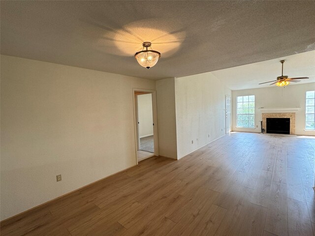 7400 Bellerive Dr Unit 1004, Houston, TX 77036 - unfurnished living room featuring wood finished floors, a ceiling fan, a fireplace with flush hearth, and a textured ceiling