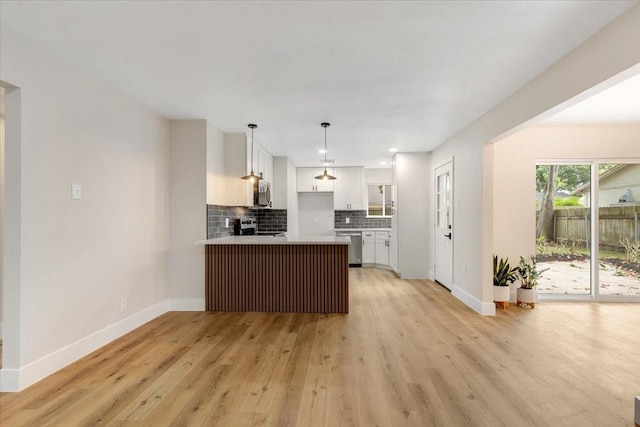2506 Swan Ct, Houston, TX 77058 - kitchen with appliances with stainless steel finishes, white cabinetry, a peninsula, light wood-style flooring, and baseboards