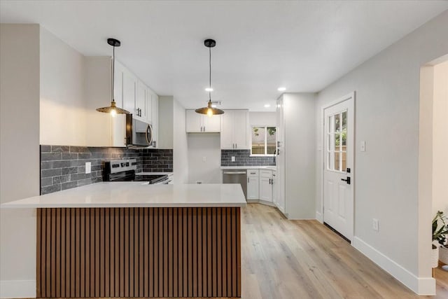 2506 Swan Ct, Houston, TX 77058 - kitchen with stainless steel appliances, a peninsula, tasteful backsplash, light wood-style flooring, and white cabinets