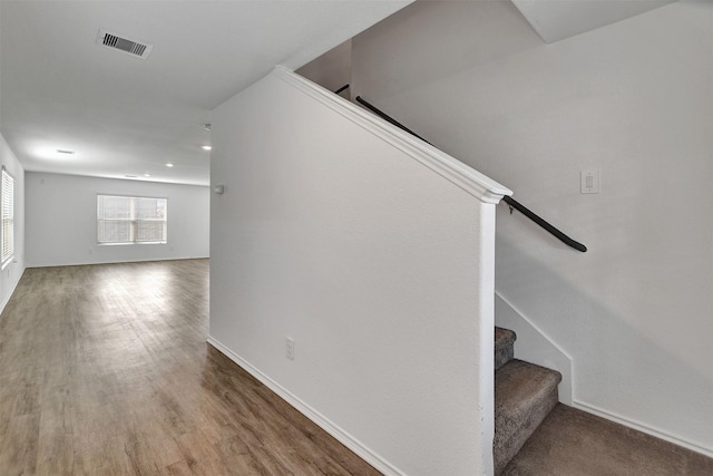 staircase with visible vents, wood finished floors, baseboards, and recessed lighting