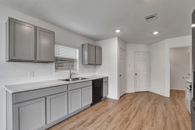 kitchen with dishwasher, gray cabinets, a sink, light wood-style floors, and light countertops