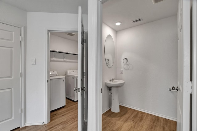 bathroom featuring washer and clothes dryer, wood finished floors, a sink, and baseboards