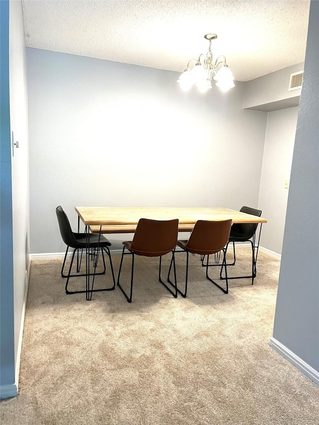 carpeted dining area featuring a chandelier, baseboards, and a textured ceiling