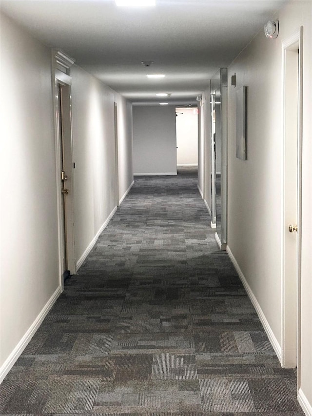 corridor featuring baseboards and carpet flooring