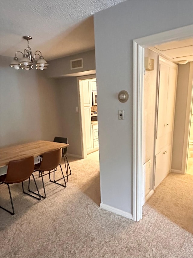 dining space featuring light colored carpet, a chandelier, and baseboards