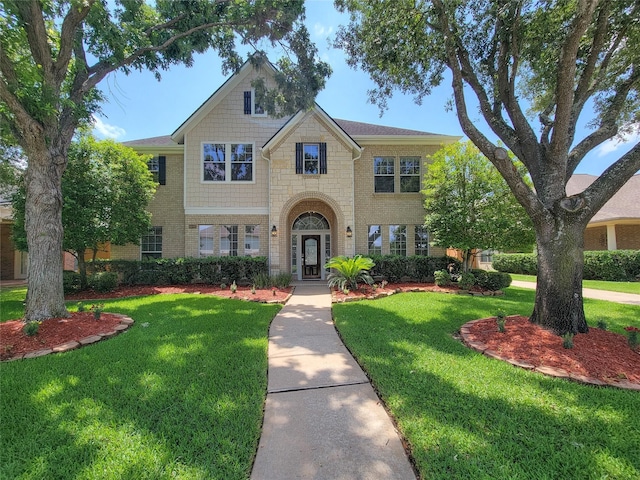 view of front of home featuring a front yard, stone siding, and brick siding