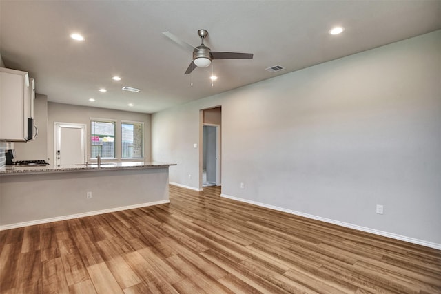 unfurnished living room featuring light wood-style floors, a ceiling fan, a sink, recessed lighting, and baseboards