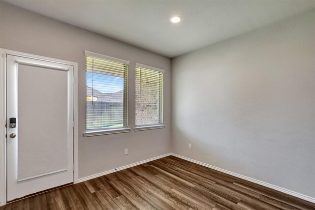 empty room featuring dark wood-style flooring, baseboards, and recessed lighting