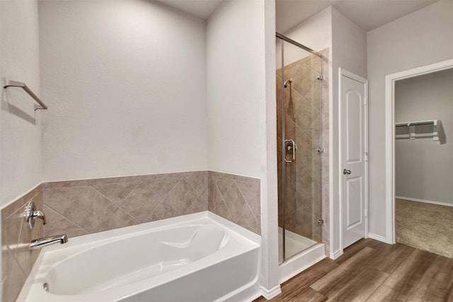 full bath featuring a stall shower, wood finished floors, a bath, and a walk in closet