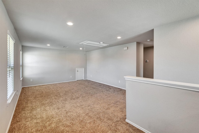 carpeted spare room featuring attic access, recessed lighting, and baseboards