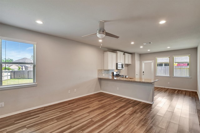 kitchen with stainless steel appliances, wood finished floors, white cabinets, a ceiling fan, and light stone countertops