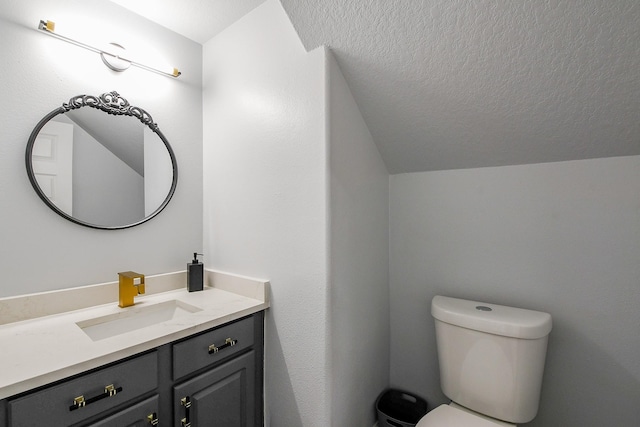 half bath with lofted ceiling, vanity, toilet, and a textured ceiling