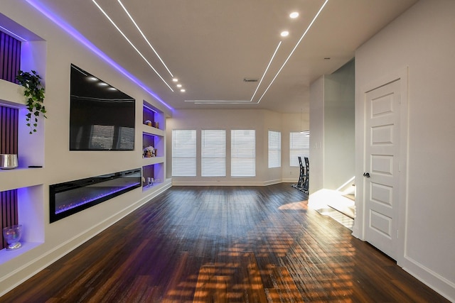 unfurnished living room featuring wood finished floors, baseboards, a glass covered fireplace, and recessed lighting