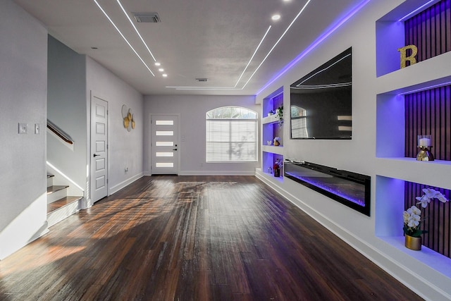 unfurnished living room with wood finished floors, stairway, a glass covered fireplace, and baseboards