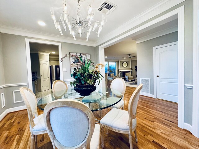 dining area featuring a chandelier, light wood-style floors, ornamental molding, and baseboards