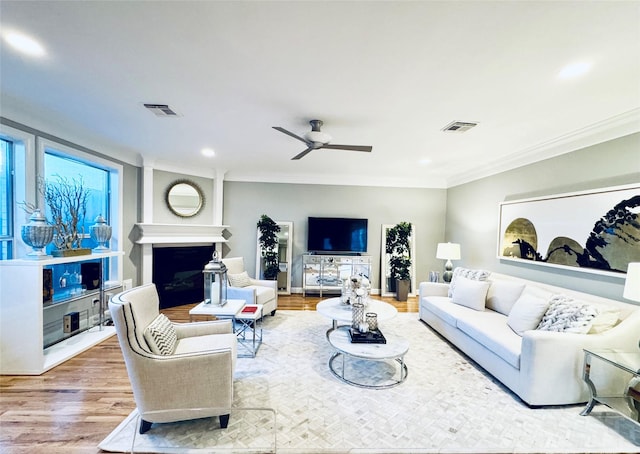 living room featuring crown molding, a fireplace, wood finished floors, recessed lighting, and ceiling fan