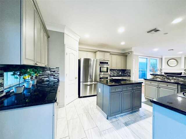 kitchen with appliances with stainless steel finishes, a kitchen island, backsplash, recessed lighting, and crown molding