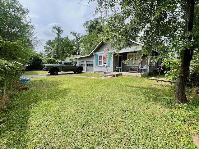 1227 W 25th St, Houston, TX 77008 - view of green lawn featuring an attached garage and a porch