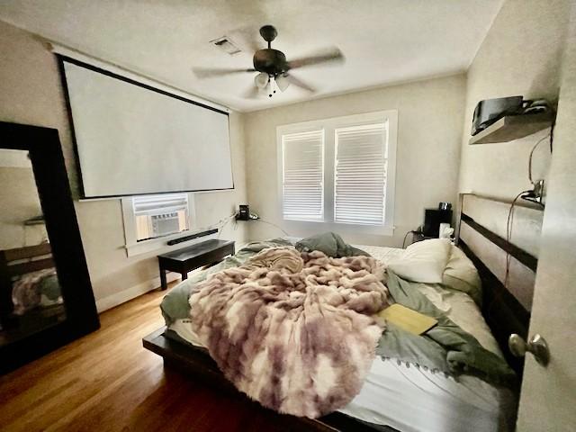 1227 W 25th St, Houston, TX 77008 - bedroom featuring wood finished floors, cooling unit, and a ceiling fan