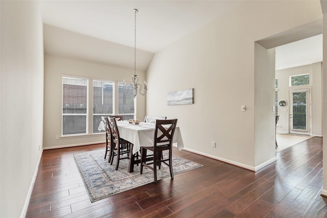 dining space with a chandelier, baseboards, dark wood-type flooring, and vaulted ceiling