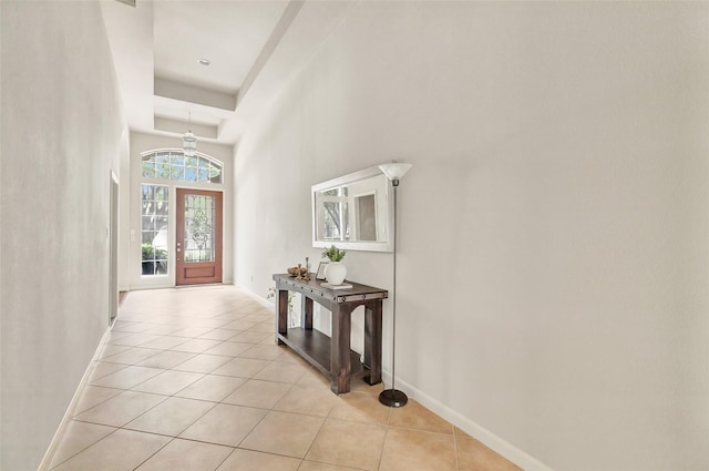 foyer entrance featuring light tile patterned floors, baseboards, a chandelier, and a high ceiling