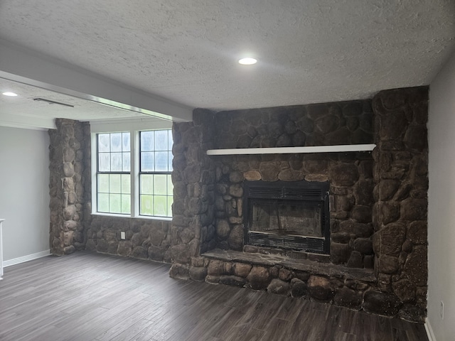 1305 Saint Lawrence River Rd, Conroe, TX 77316 - unfurnished living room with wood finished floors, a textured ceiling, a stone fireplace, baseboards, and recessed lighting