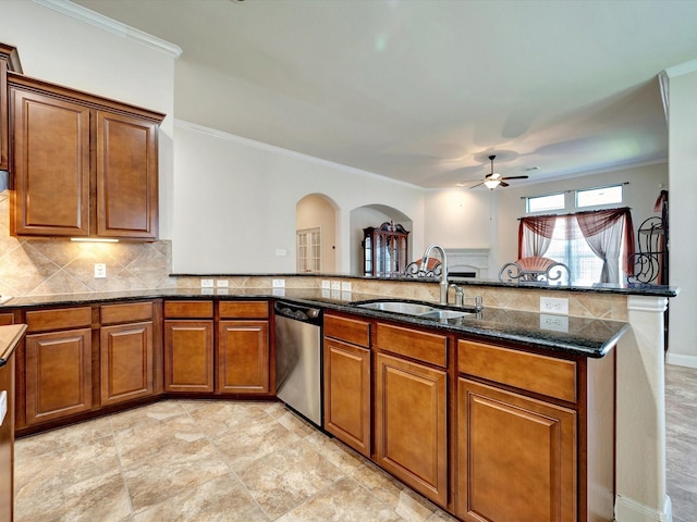 kitchen featuring a sink, stainless steel dishwasher, arched walkways, a ceiling fan, and brown cabinetry