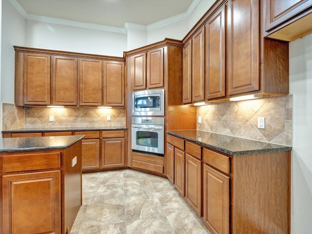 kitchen with stainless steel appliances, brown cabinetry, crown molding, dark stone countertops, and backsplash