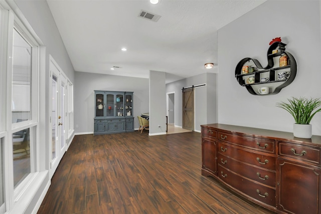 hall featuring a barn door, dark wood-style floors, baseboards, and recessed lighting