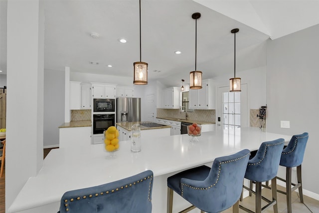 kitchen with black appliances, tasteful backsplash, a sink, recessed lighting, and white cabinets