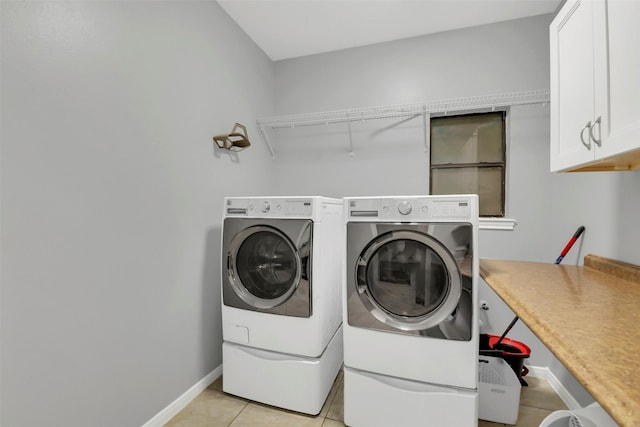 clothes washing area featuring cabinet space, light tile patterned floors, washer and dryer, and baseboards