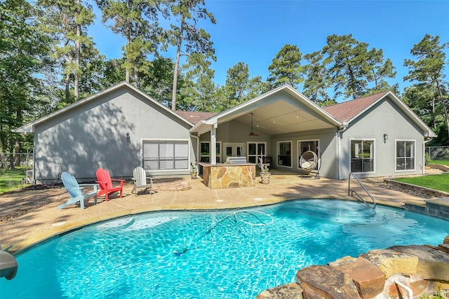 rear view of property with a patio area, area for grilling, an outdoor pool, and stucco siding