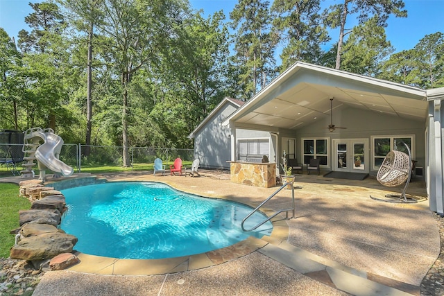view of swimming pool with a water slide, fence, a patio area, and a ceiling fan