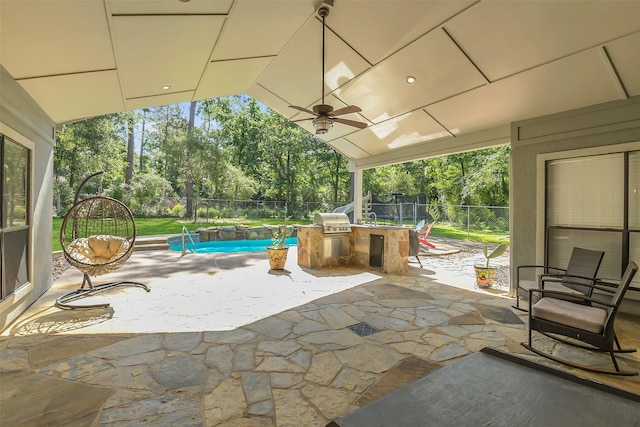 view of patio / terrace featuring an outdoor kitchen, a fenced backyard, area for grilling, view of wooded area, and a ceiling fan