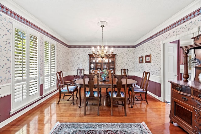19827 Timberwind Ln, Houston, TX 77094 - dining room featuring wallpapered walls, a chandelier, wainscoting, crown molding, and wood finished floors