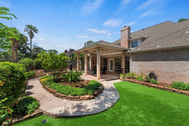 19827 Timberwind Ln, Houston, TX 77094 - back of house featuring brick siding, a chimney, a lawn, a shingled roof, and a patio