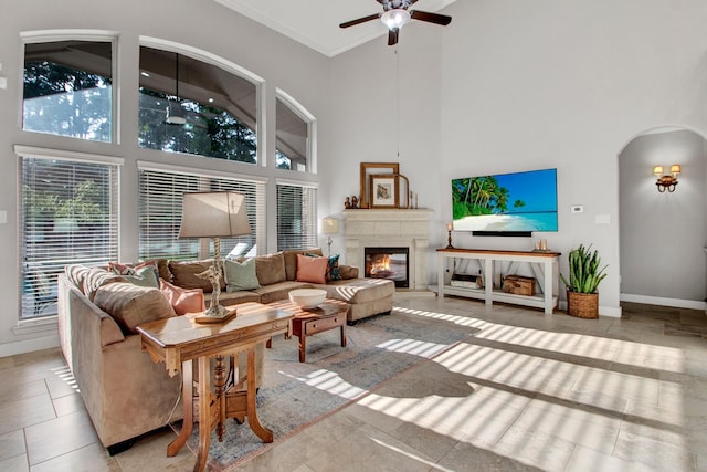 514 Chirping Sparrow Ct, Pinehurst, TX 77362 - tiled living area with a high ceiling, arched walkways, ceiling fan, a glass covered fireplace, and baseboards