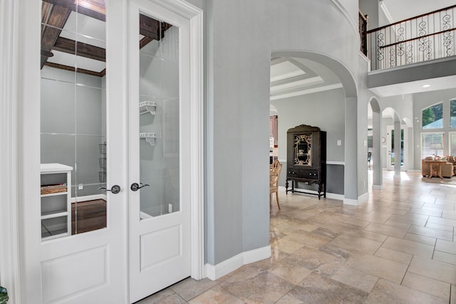 514 Chirping Sparrow Ct, Pinehurst, TX 77362 - foyer entrance with arched walkways, baseboards, stone tile floors, a towering ceiling, and french doors