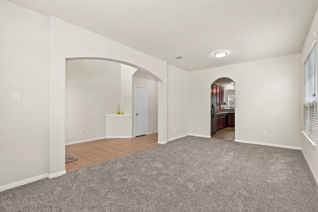 30722 Lavender Trace Dr, Spring, TX 77386 - spare room featuring light tile patterned flooring, light colored carpet, and arched walkways