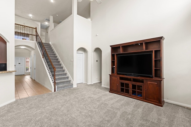 30722 Lavender Trace Dr, Spring, TX 77386 - unfurnished living room with arched walkways, stairs, a towering ceiling, carpet flooring, and tile patterned flooring