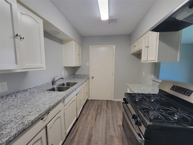 kitchen featuring stainless steel range with gas cooktop, under cabinet range hood, a sink, dark wood-style floors, and white cabinets