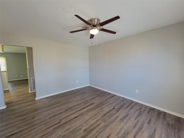unfurnished room featuring dark wood-style flooring, ceiling fan, and baseboards