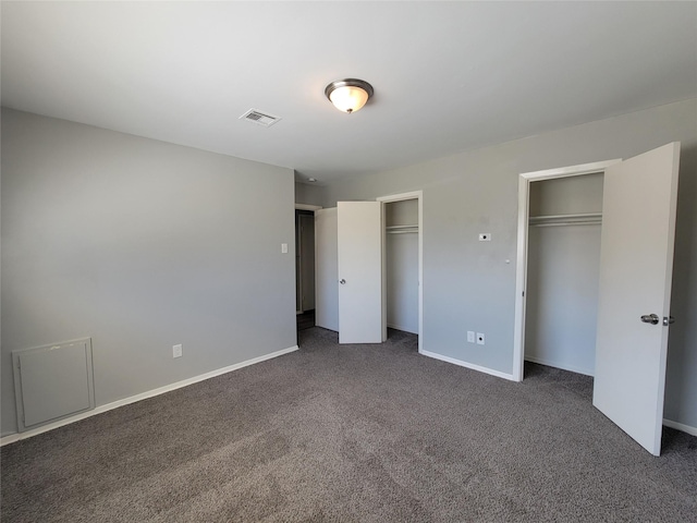 unfurnished bedroom featuring two closets, dark carpet, and baseboards