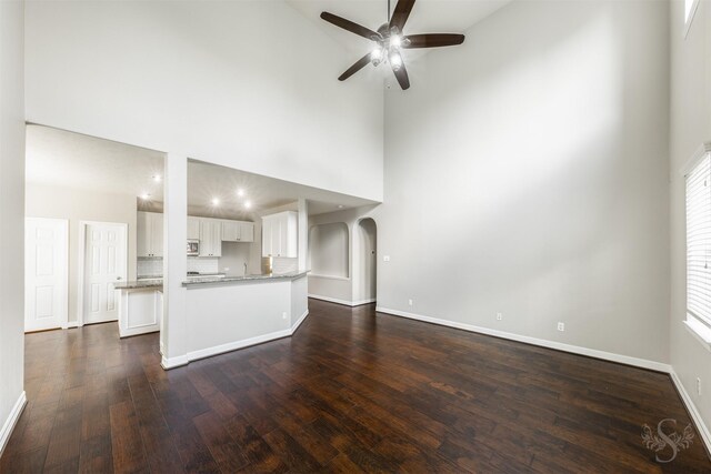 3722 Rocky Ledge Ln, Katy, TX 77494 - unfurnished living room with ceiling fan, a towering ceiling, dark wood finished floors, baseboards, and arched walkways
