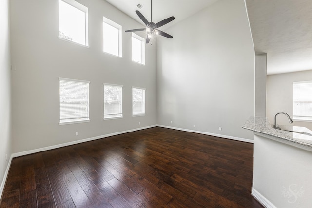3722 Rocky Ledge Ln, Katy, TX 77494 - unfurnished living room with a sink, ceiling fan, dark wood-type flooring, baseboards, and a towering ceiling
