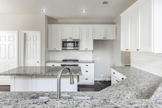 3722 Rocky Ledge Ln, Katy, TX 77494 - kitchen with stainless steel microwave, a sink, white cabinets, light stone countertops, and recessed lighting