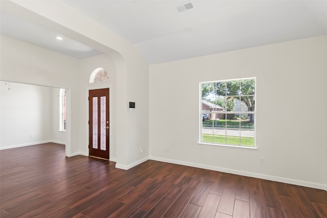 foyer entrance featuring dark wood-type flooring, baseboards, arched walkways, and lofted ceiling