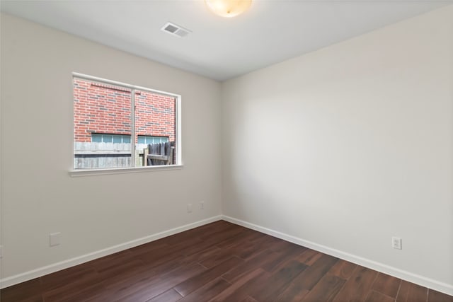 spare room featuring dark wood-style floors and baseboards